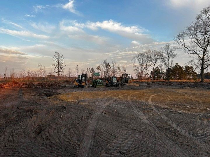 A group of tractors are parked in a dirt field.