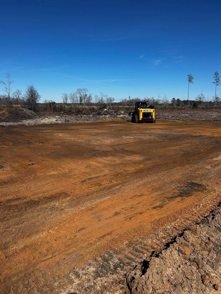 A bulldozer is driving down a dirt road in a field.