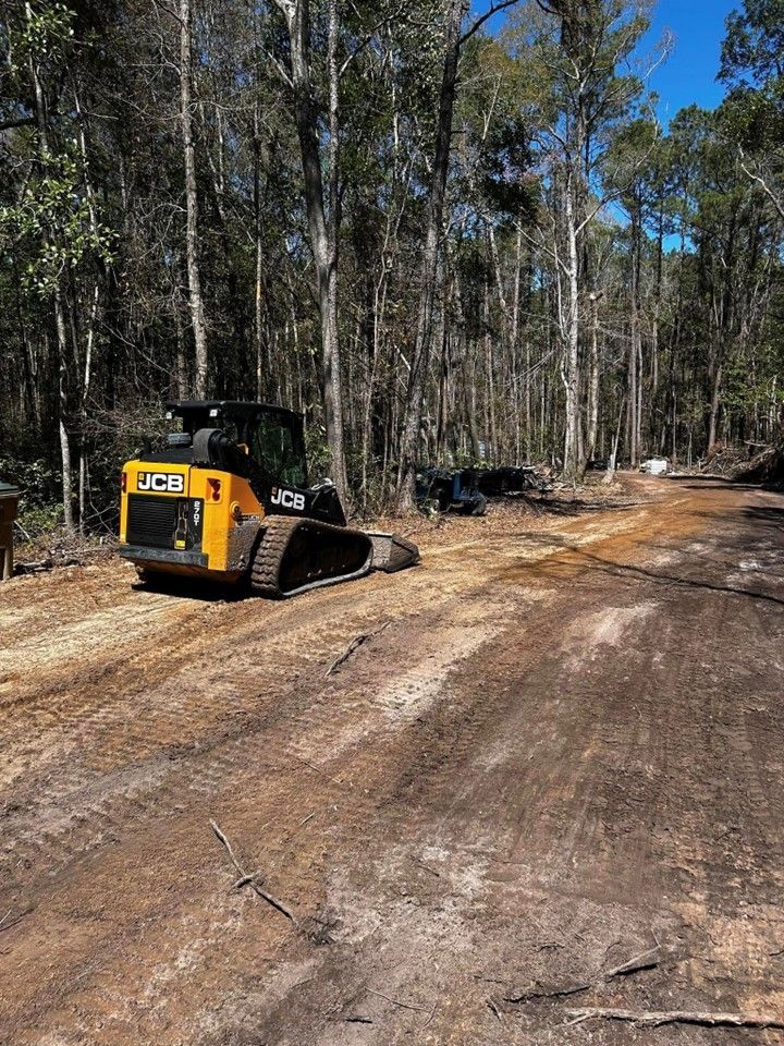 A bulldozer is driving down a dirt road in the woods.