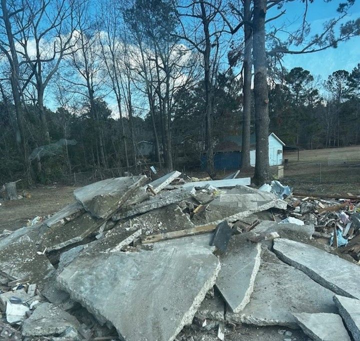 A pile of rubble in a field with trees in the background