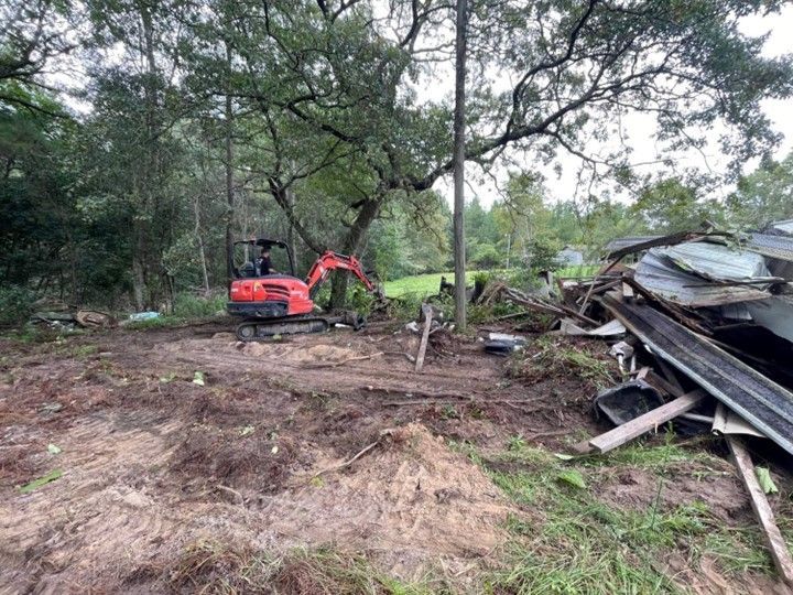 A red excavator is sitting in the middle of a dirt field.