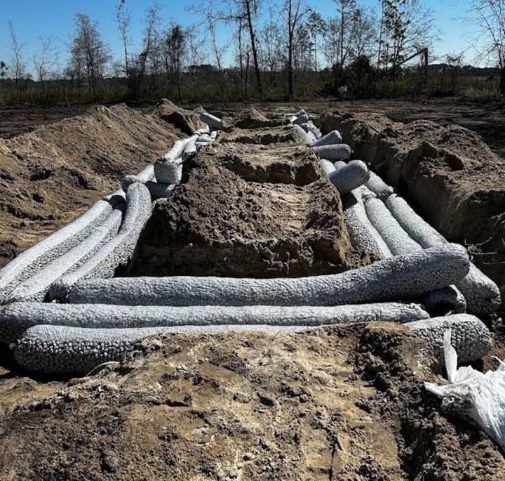 A bunch of pipes are laying in the dirt