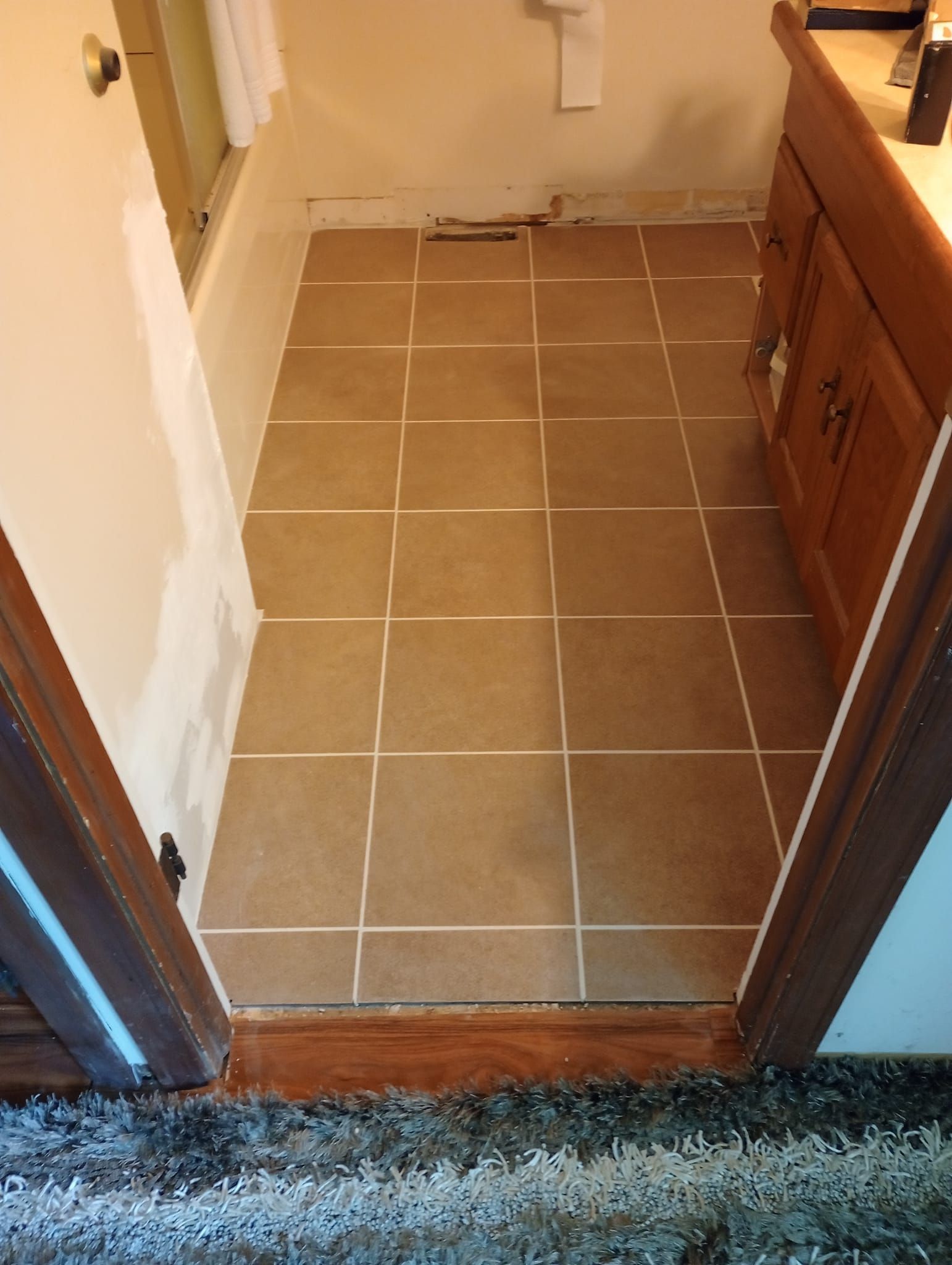 A bathroom with a tiled floor and wooden cabinets