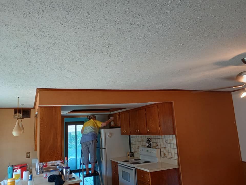 A man is painting the ceiling of a kitchen