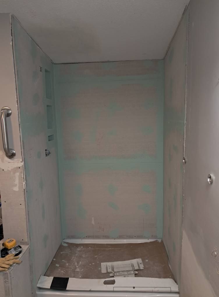 A bathroom under construction with a bathtub and a shower stall.