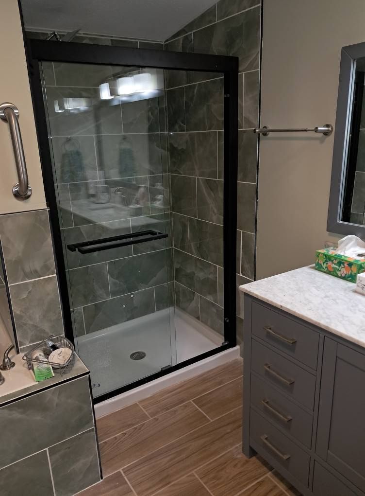 A bathroom with a walk in shower and a sink.