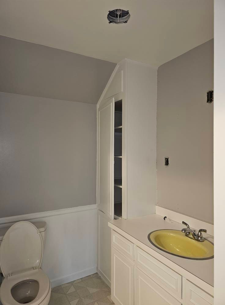 A bathroom with a toilet , sink and mirror.