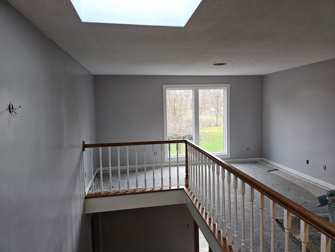 An empty room with stairs and a skylight in the ceiling.