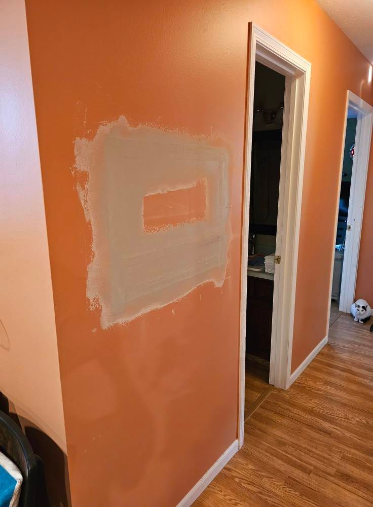 A hallway with a door and a wall with a hole in it.