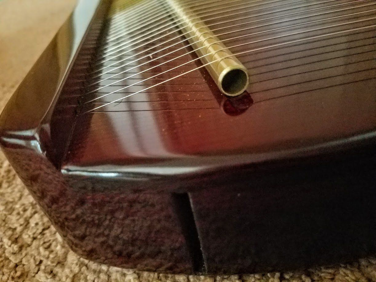 A close up of a harp with a brass tube on it.