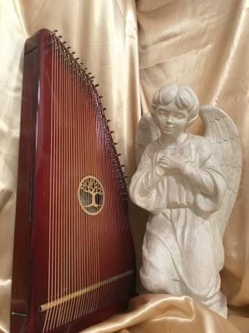 A harp is sitting next to a statue of an angel.