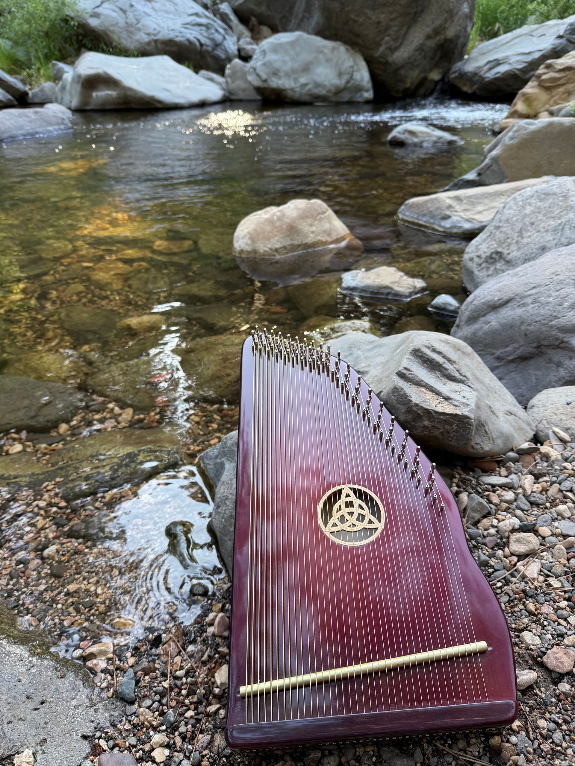 A harp is sitting on the rocks near a river.
