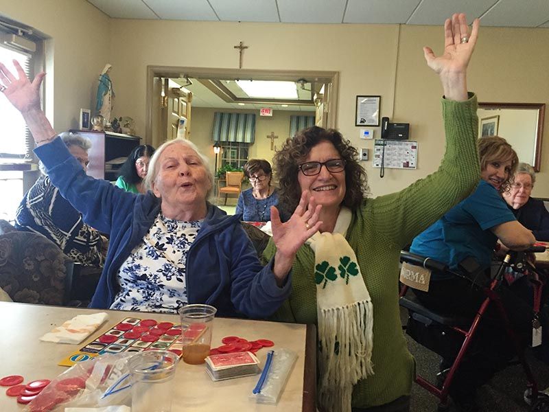 Two women are sitting at a table with their arms in the air.