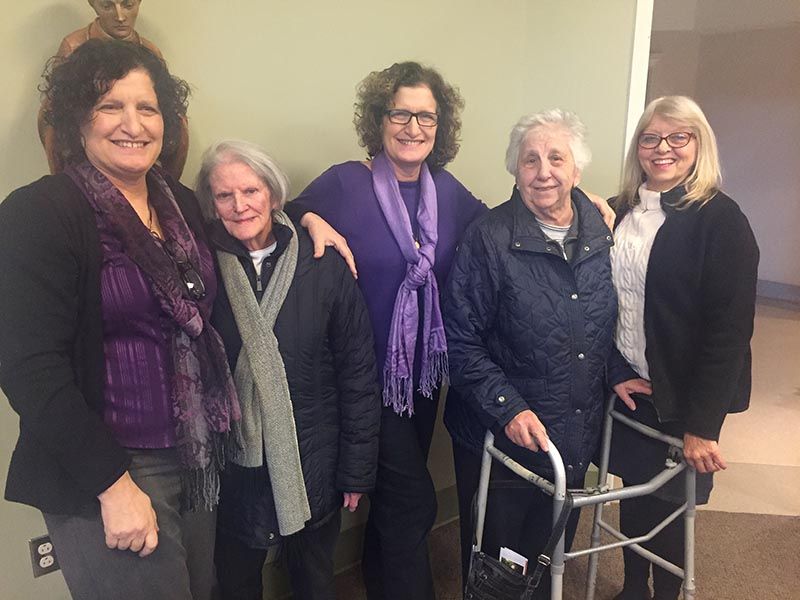 A group of women are posing for a picture with one woman using a walker.