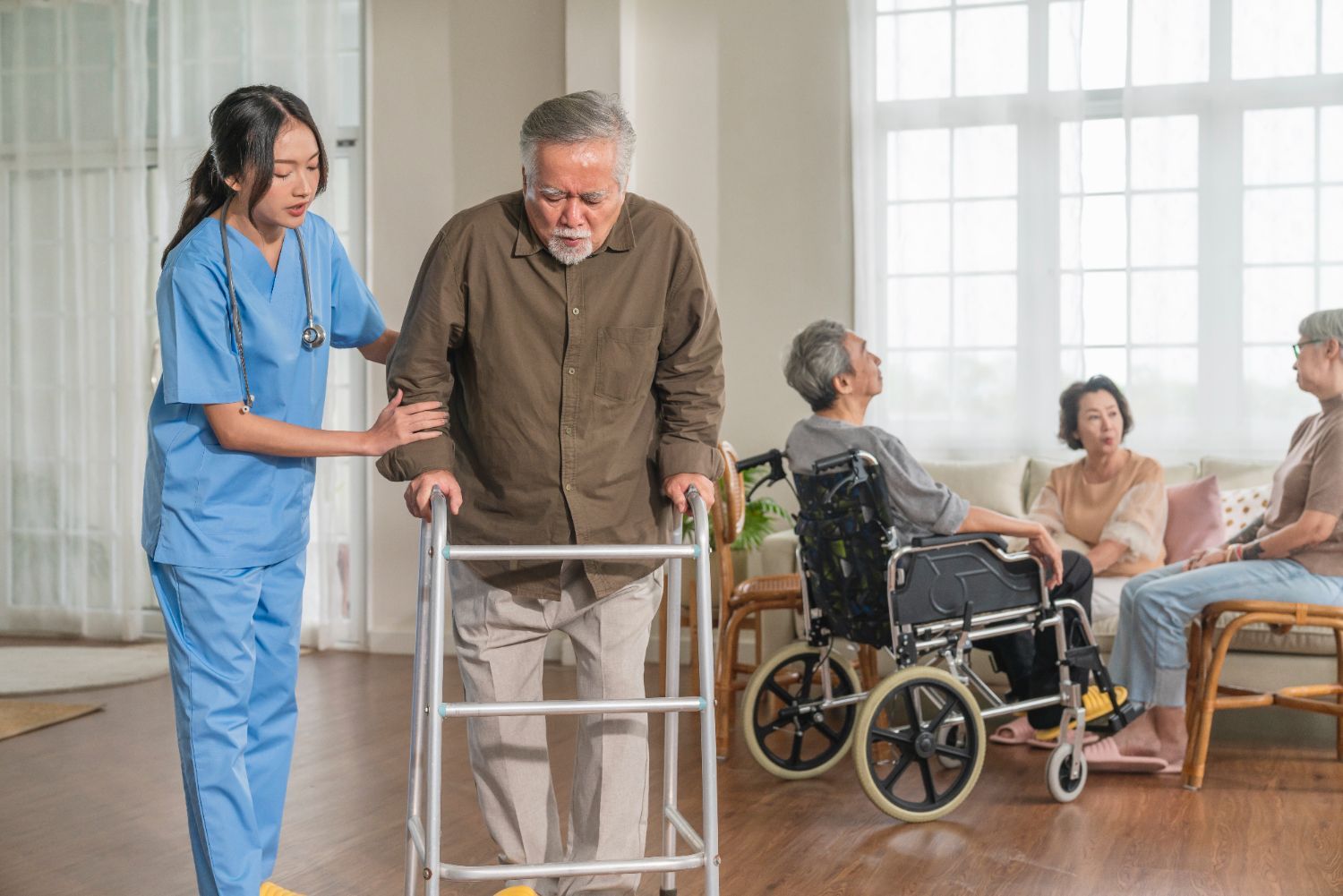 A nurse is helping an elderly man walk with a walker.