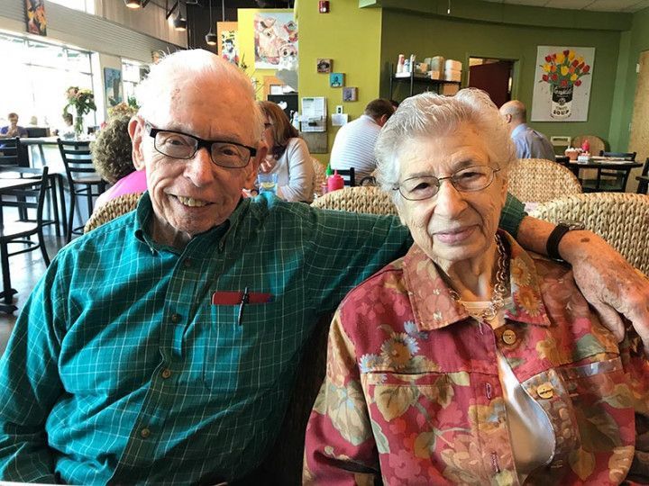A man and a woman are posing for a picture in a restaurant.