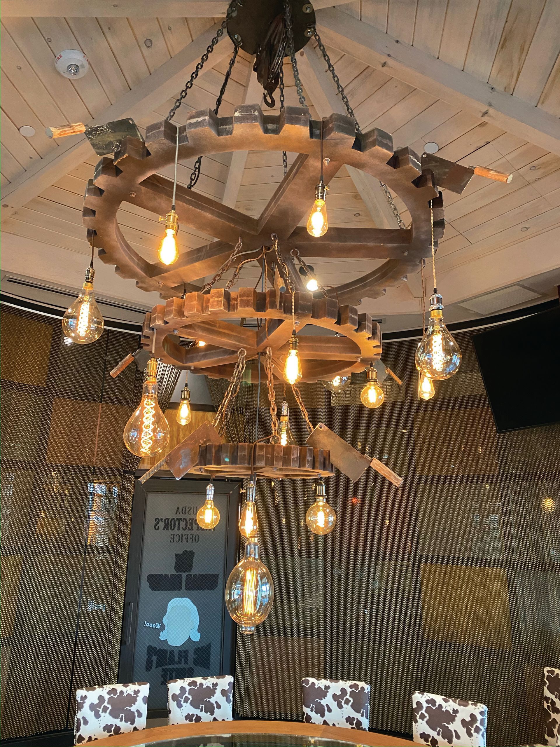 a large wooden chandelier hangs from the ceiling above a table