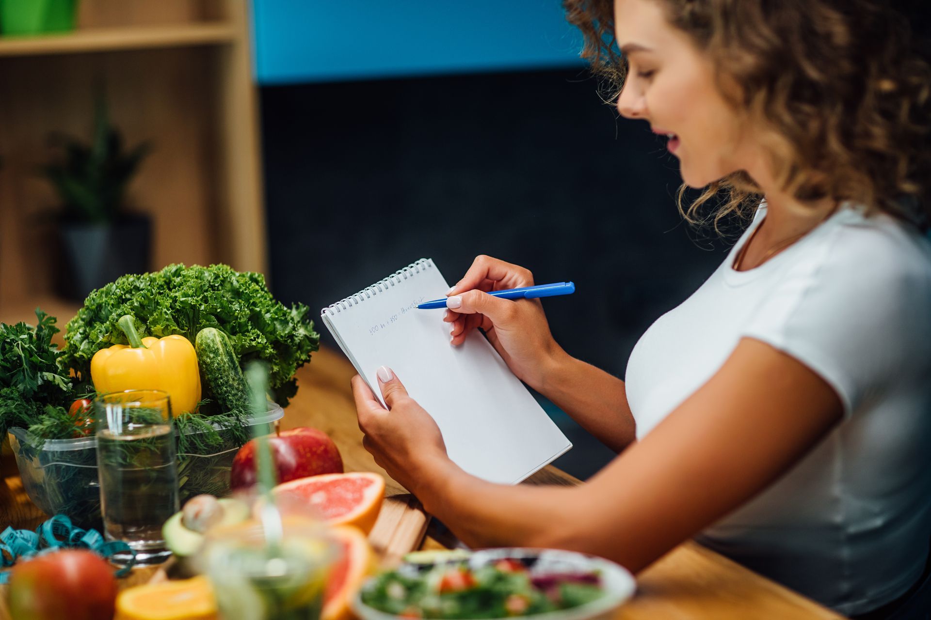 A woman is sitting at a table writing in a notebook