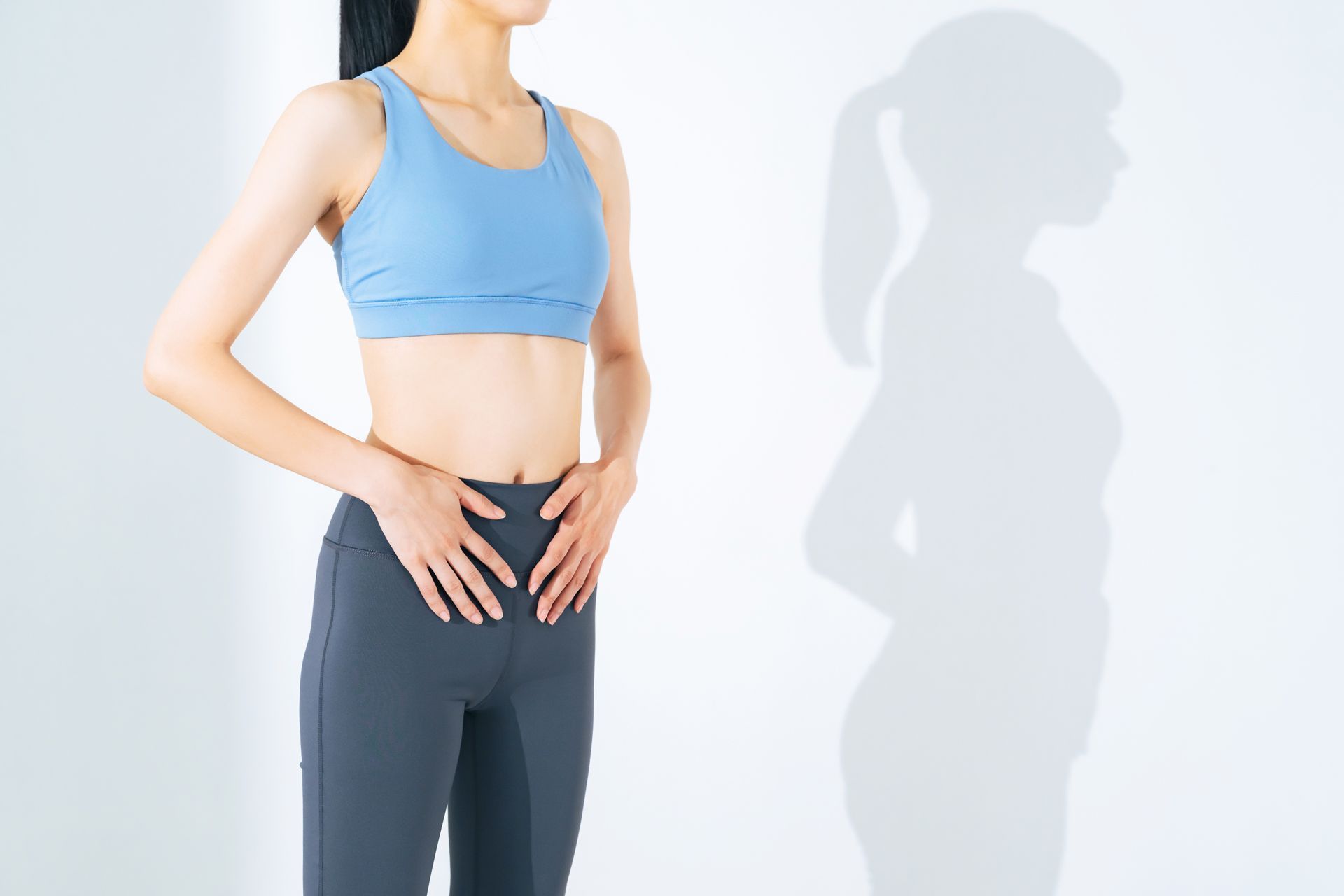 A Woman in a Blue Sports Bra is Standing Next to Her Shadow