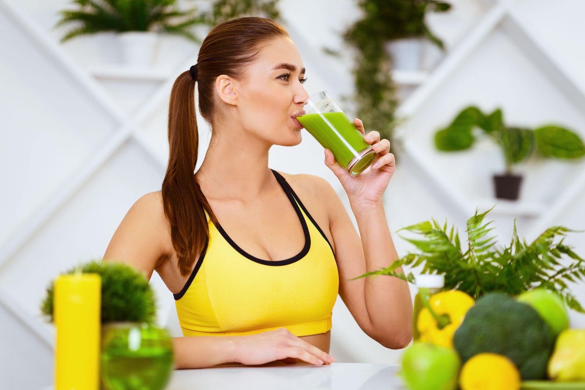 A woman is drinking a green smoothie from a glass