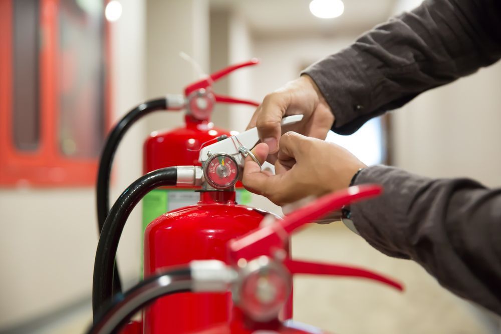A Person Is Adjusting a Fire Extinguisher in A Hallway — Fire Protection Services in Mullumbimby, NSW