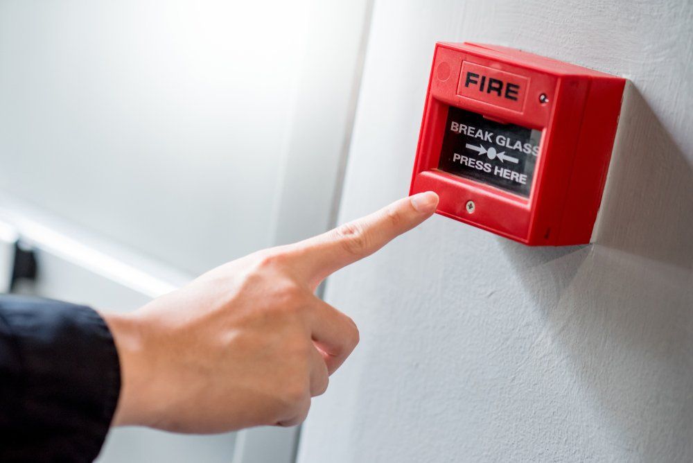 Hand Pointing at Red Fire Alarm Switch — Fire Protection Services in Ballina, NSW