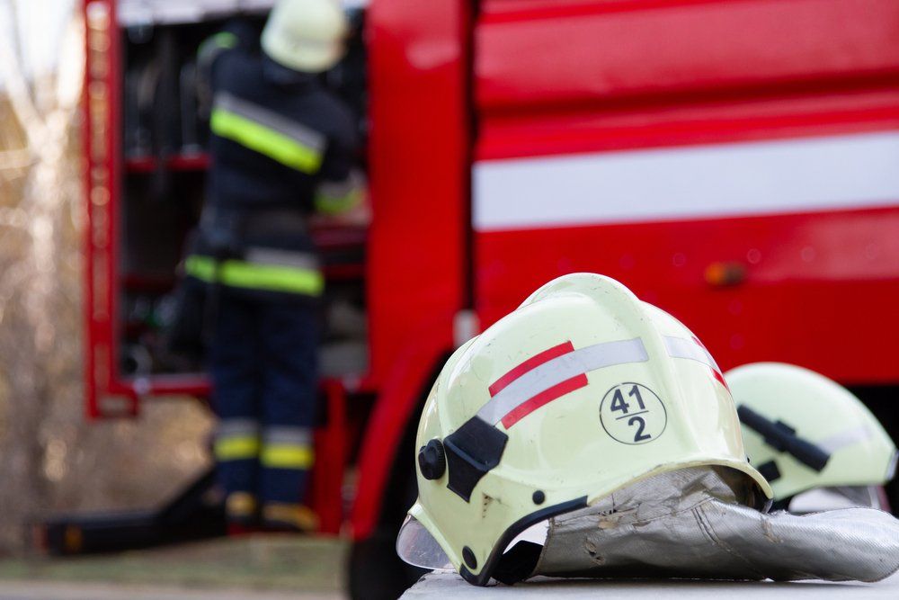 A Fireman Is Getting out Of a Fire Truck and A Helmet — Fire Protection Services in Brunswick Heads, NSW