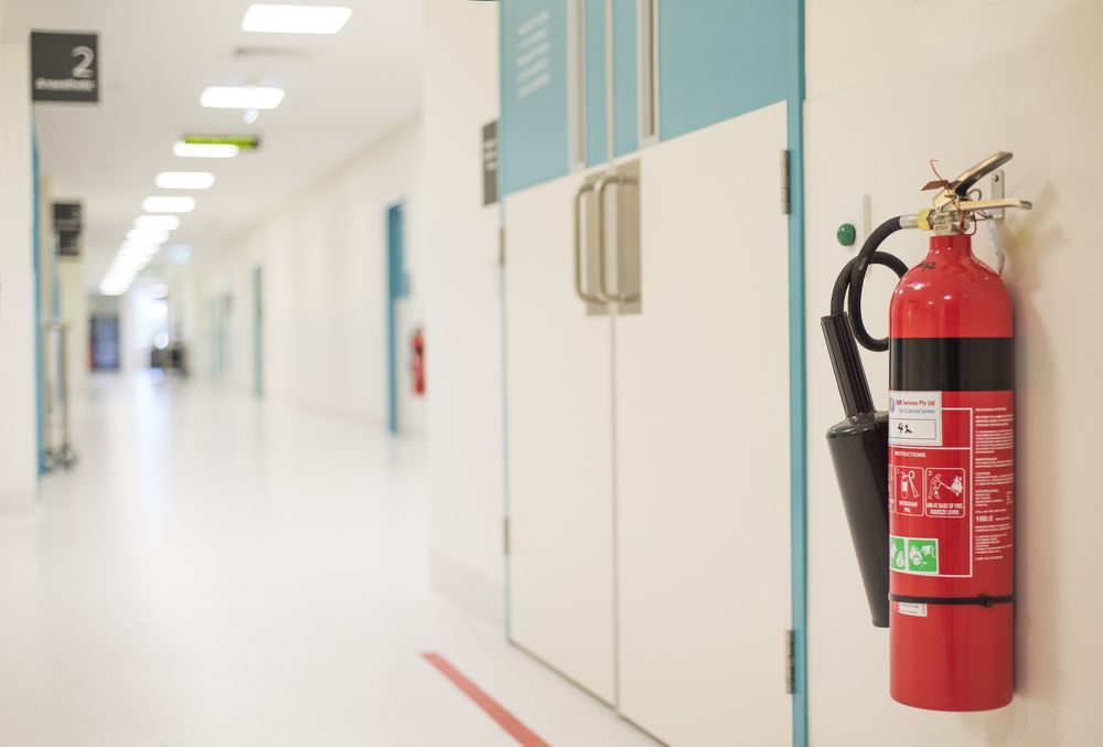 A Fire Extinguisher Is Hanging on A Door in A Hospital Hallway — Fire Protection Services in Casuarina, NSW