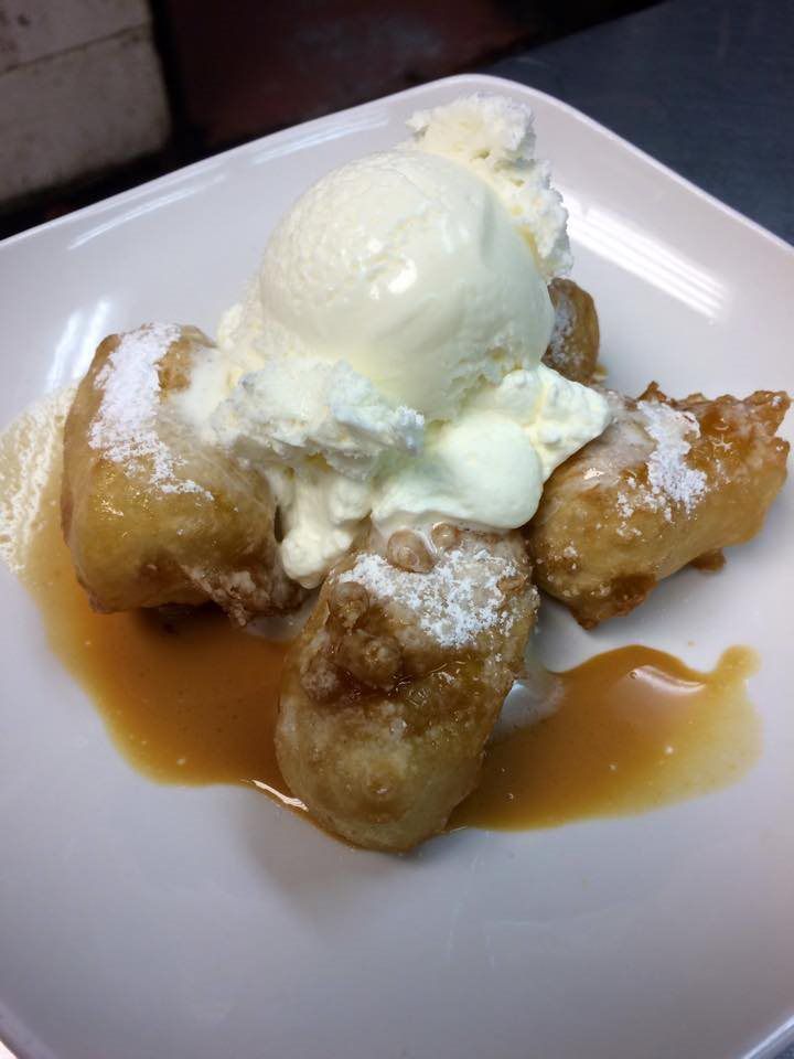 A white plate topped with fried bananas and ice cream
