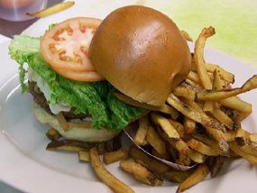 A hamburger and french fries on a white plate.