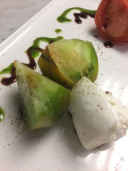 A close up of a plate of food with tomatoes and mozzarella on a table.