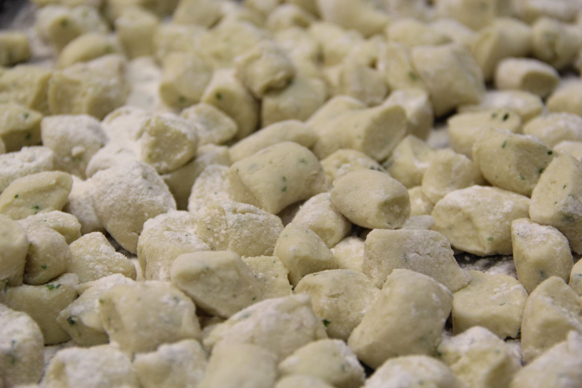 A pile of gnocchi covered in powdered sugar on a table.