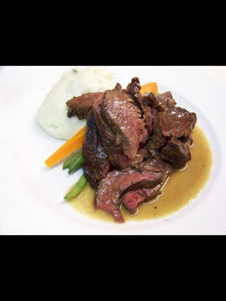 A white plate topped with steak mashed potatoes and vegetables