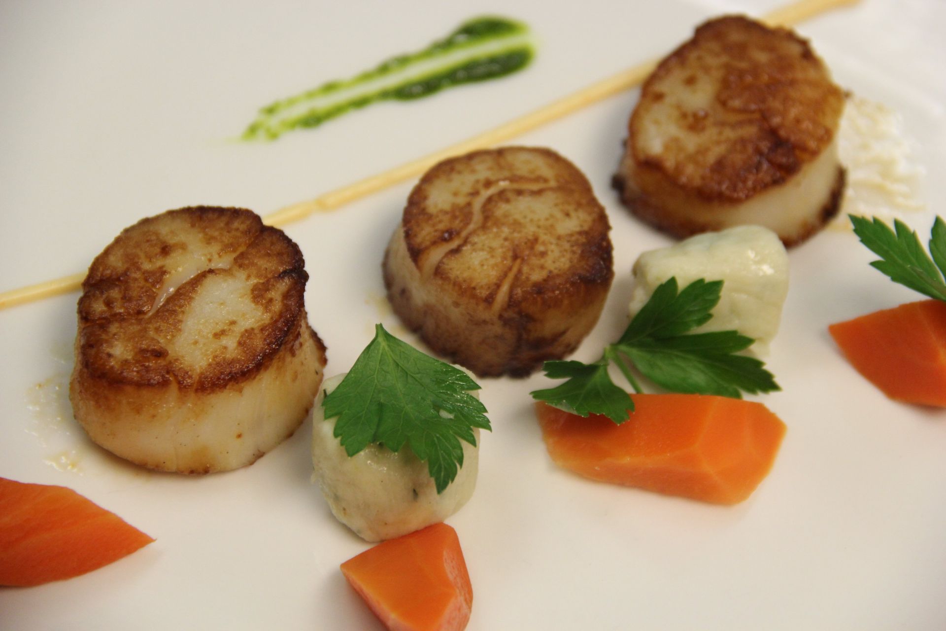 A white plate topped with scallops , carrots and parsley.