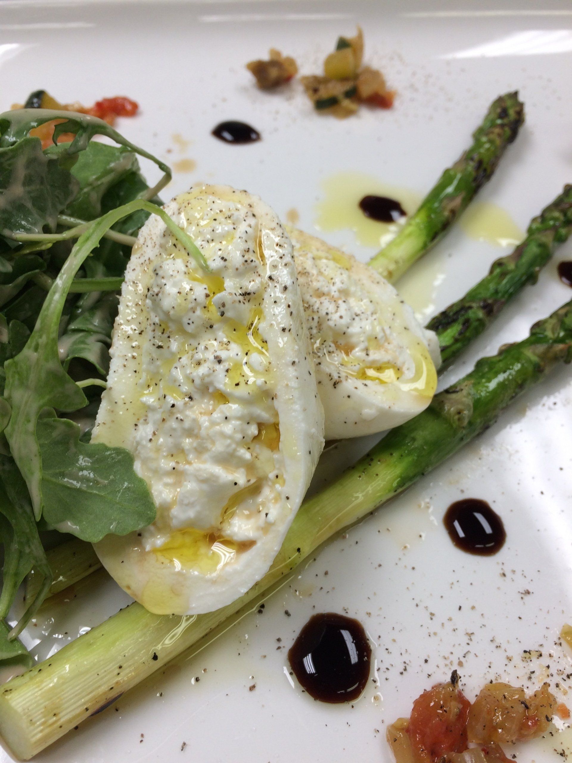 A white plate topped with asparagus and a poached egg.