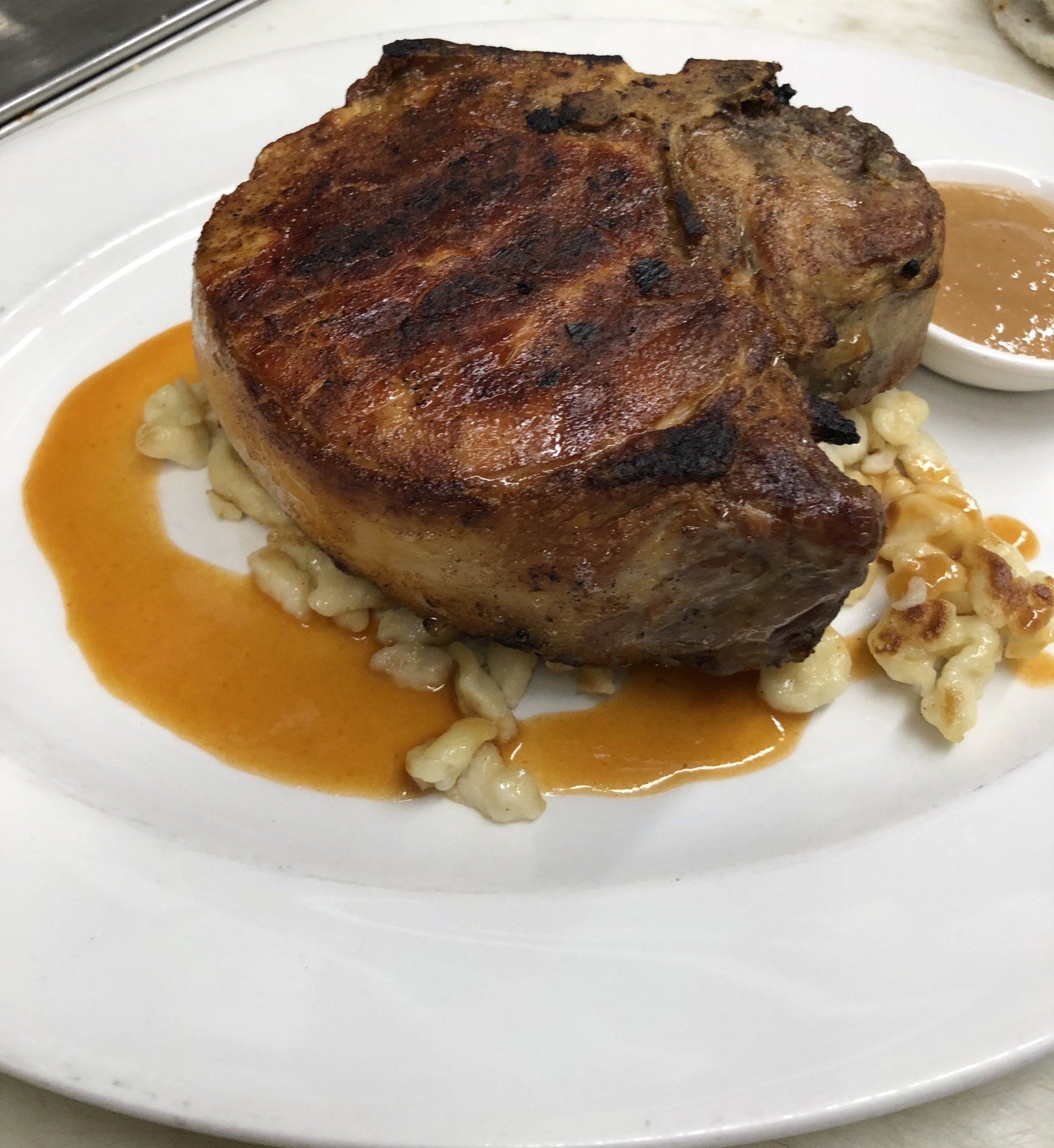 A white plate topped with a piece of meat and sauce