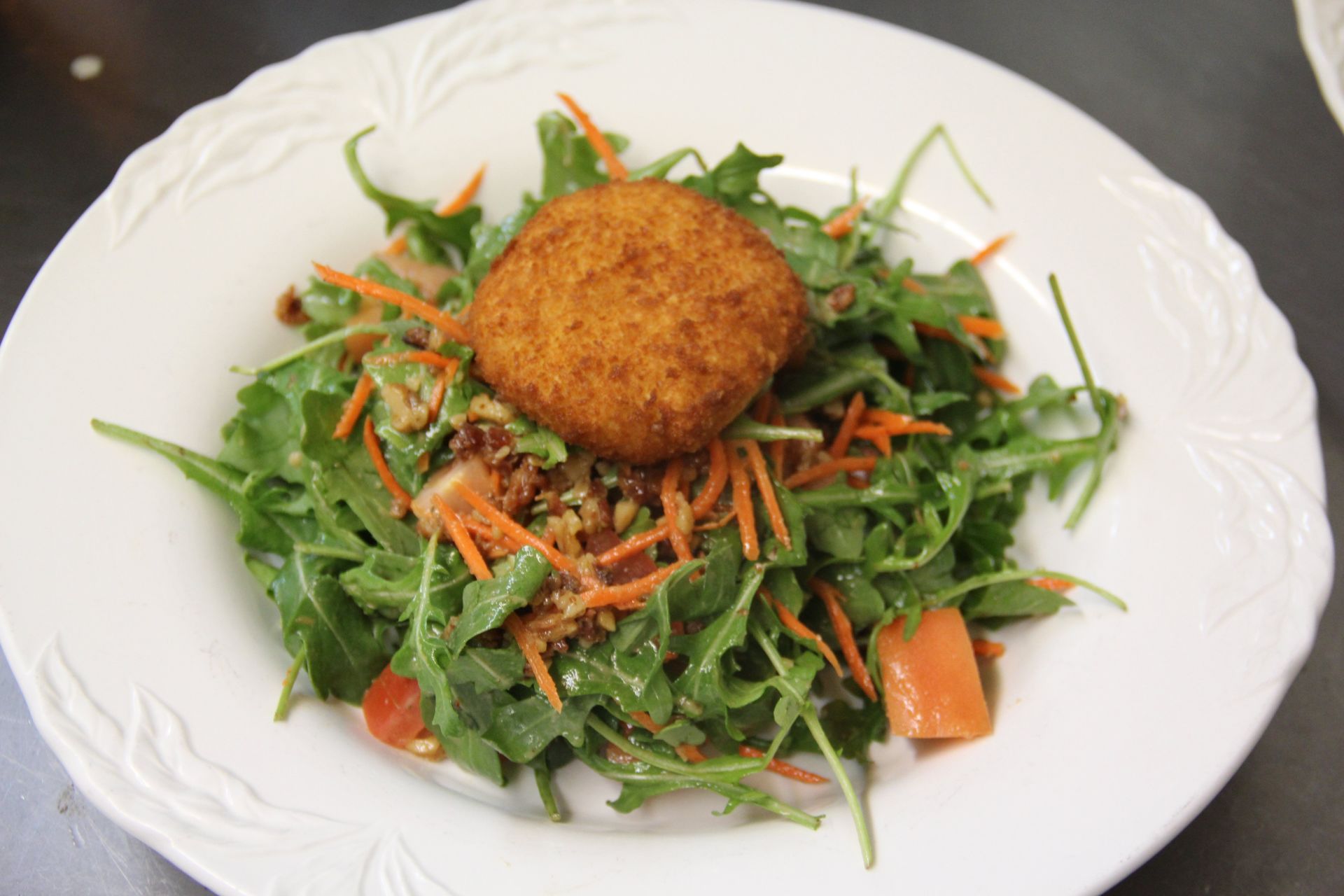A white plate topped with a salad and a fried food item