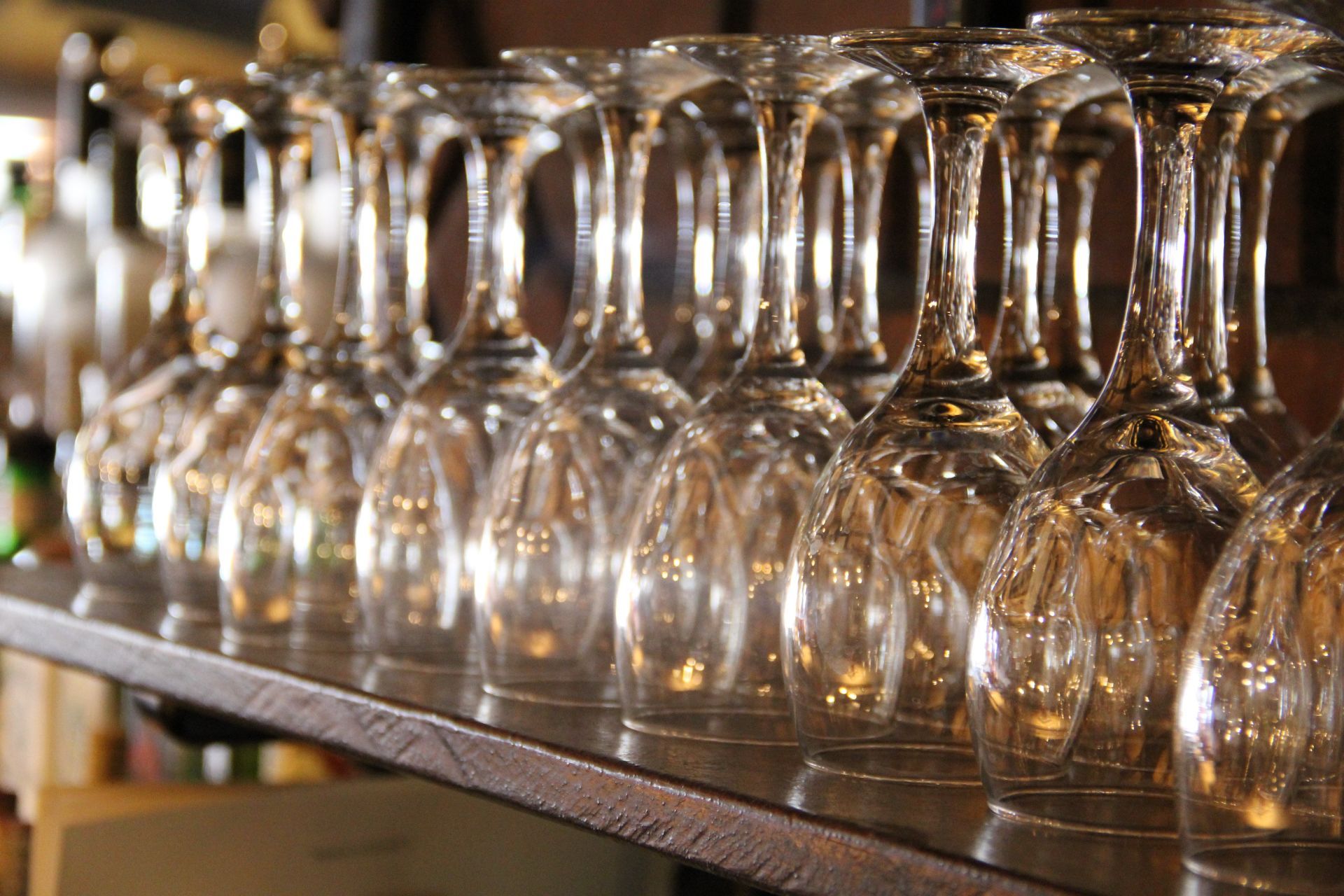 A row of wine glasses are lined up on a shelf