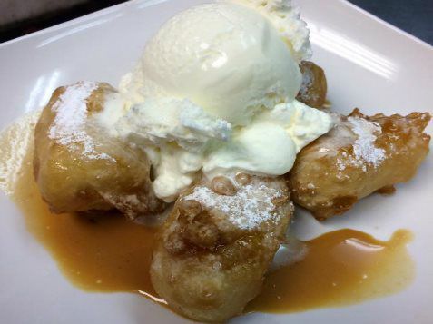 A white plate topped with fried bananas and ice cream.