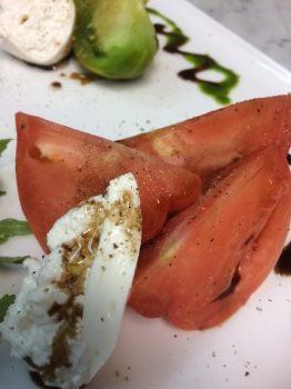 A white plate topped with sliced tomatoes and mozzarella cheese.