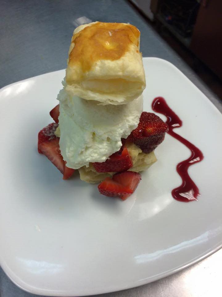 A white plate topped with a biscuit ice cream and strawberries