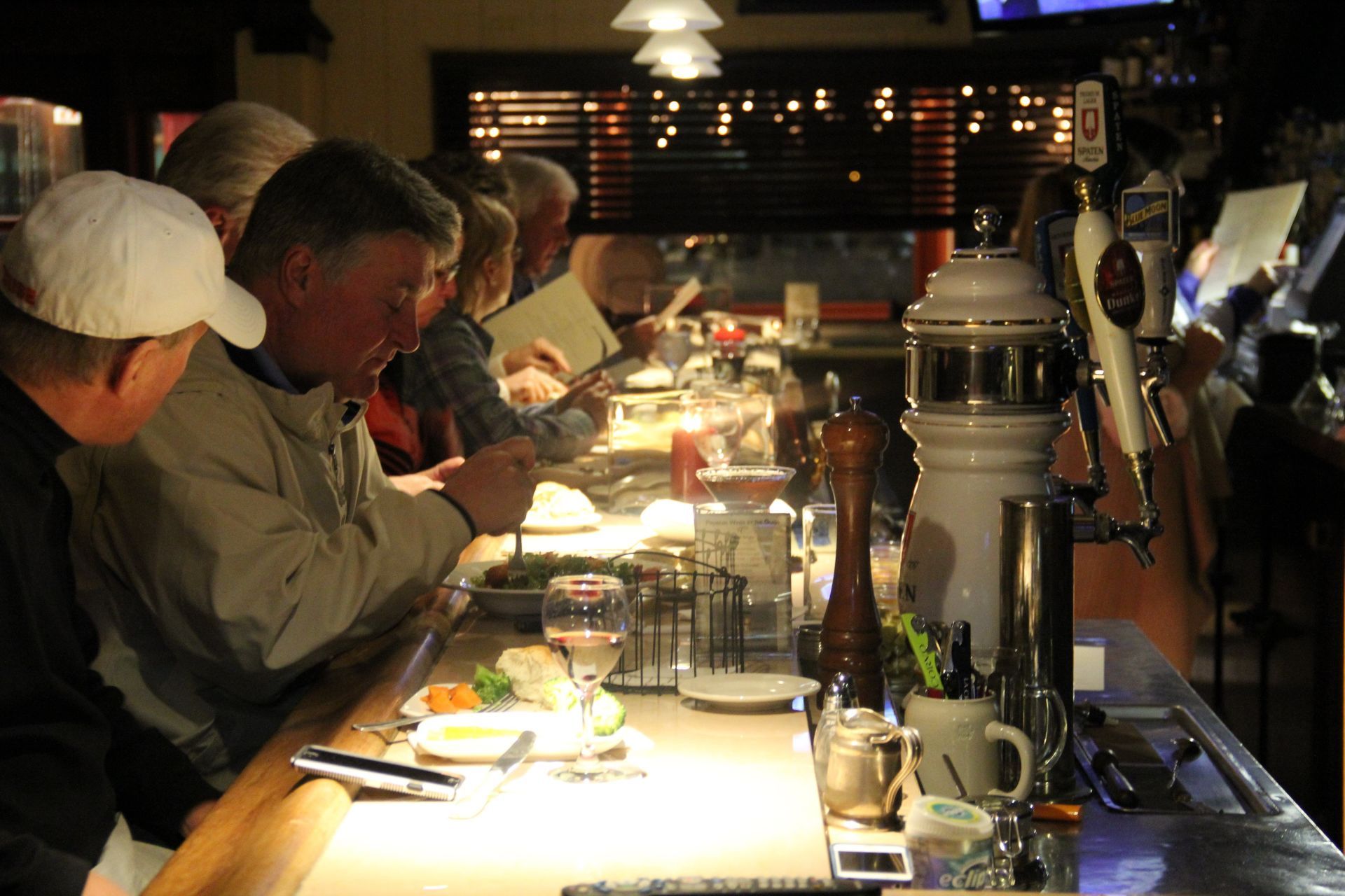 A group of people sitting at a bar looking at their phones