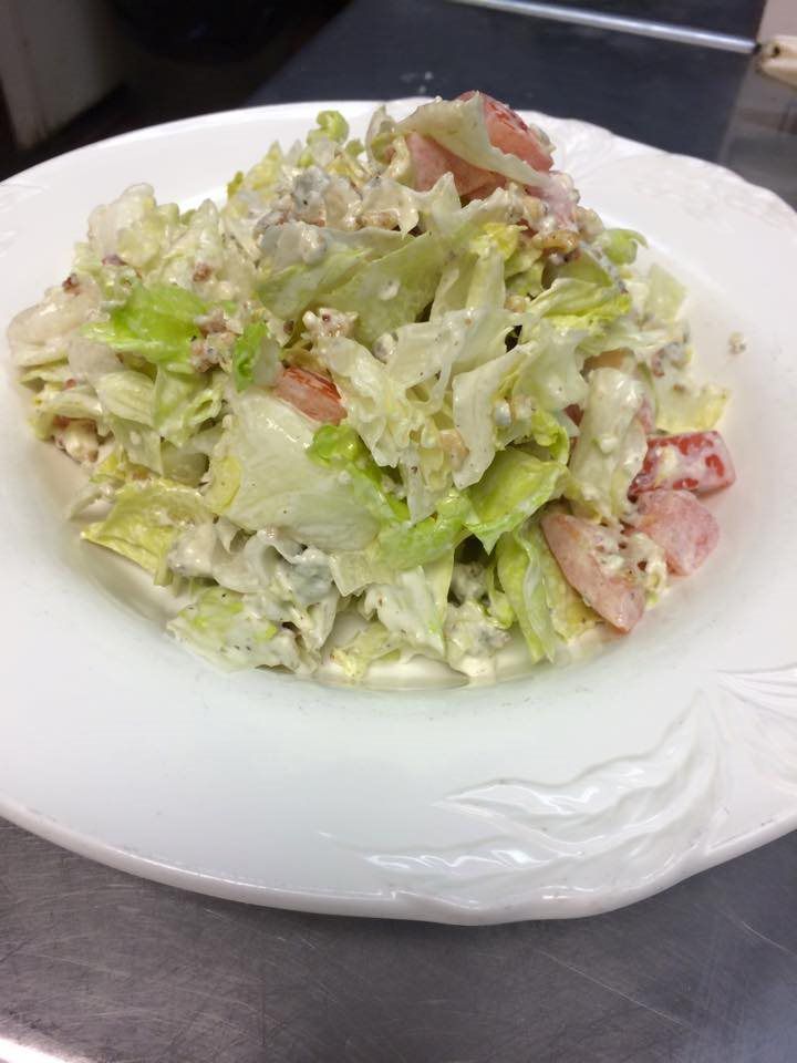 A close up of a salad on a white plate on a table.