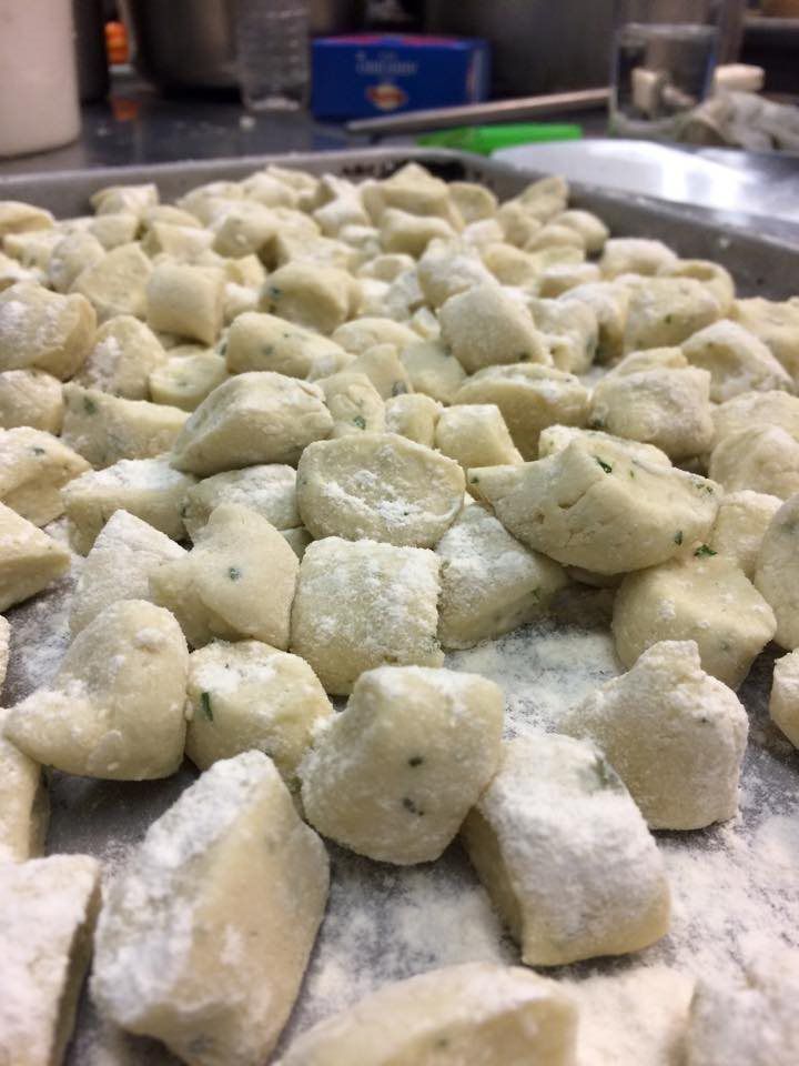 A tray of gnocchi covered in flour on a table.