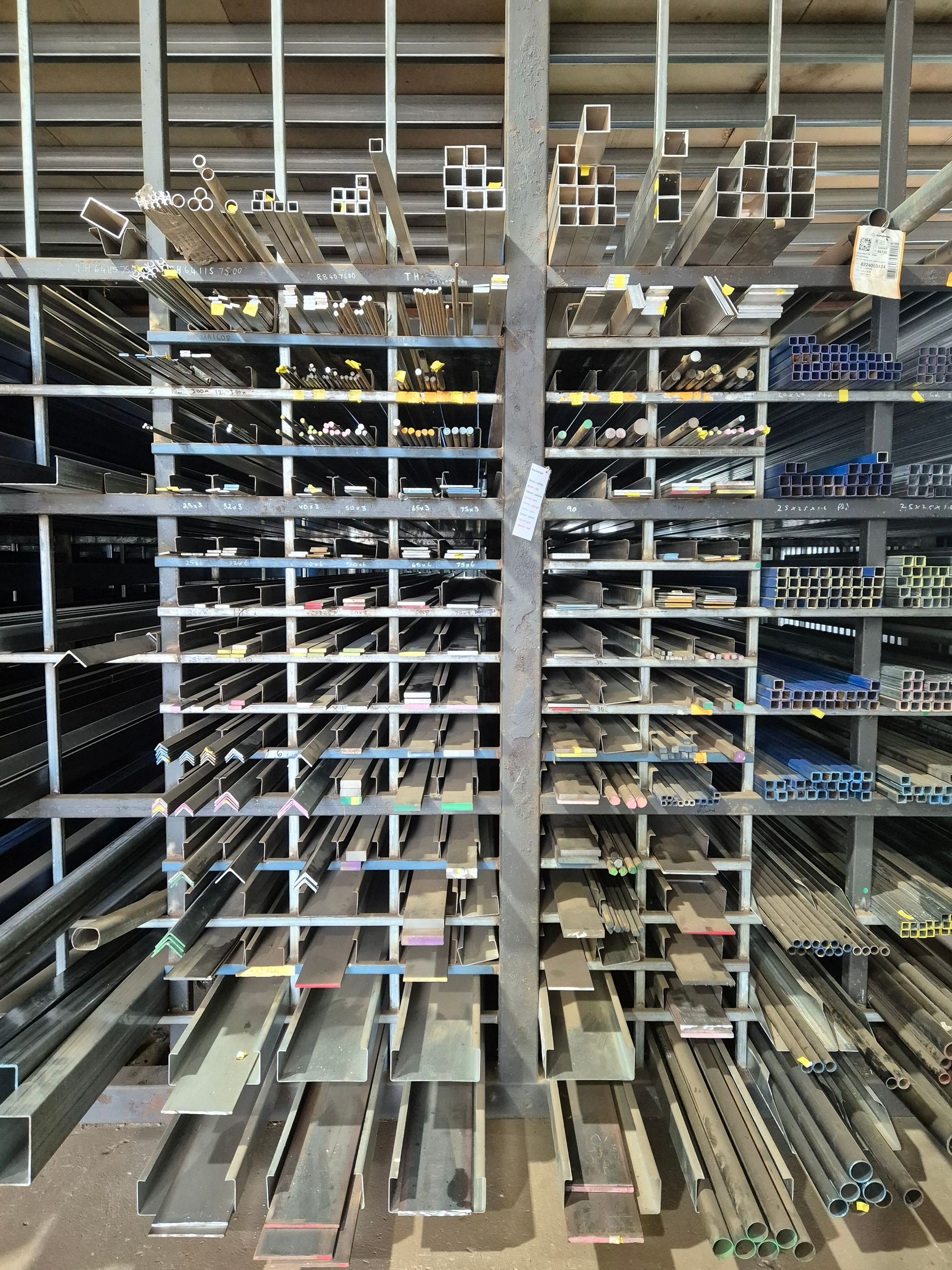 Metal beams and rods organized in shelves in a warehouse.