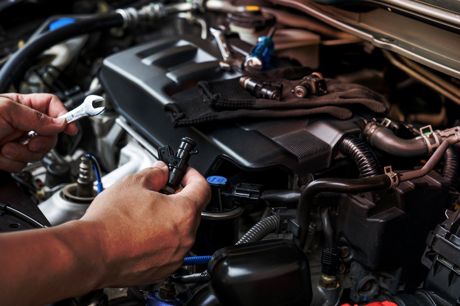 A person is working on a car engine with a wrench.