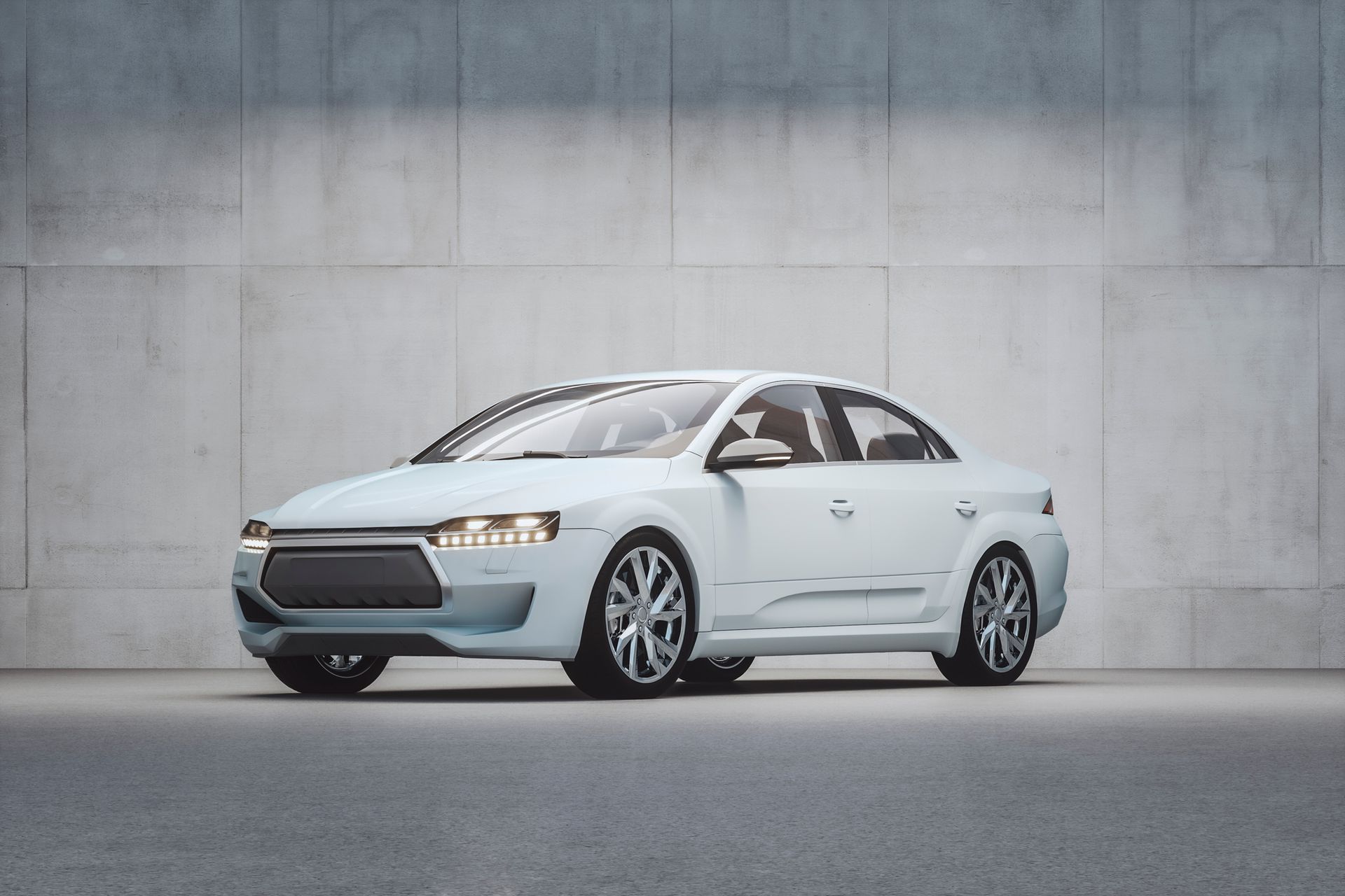 White sedan parked in front of a gray concrete wall.
