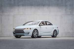 White sedan parked in front of a concrete wall.