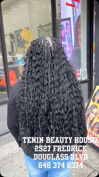A woman with long curly hair is standing in front of a store.