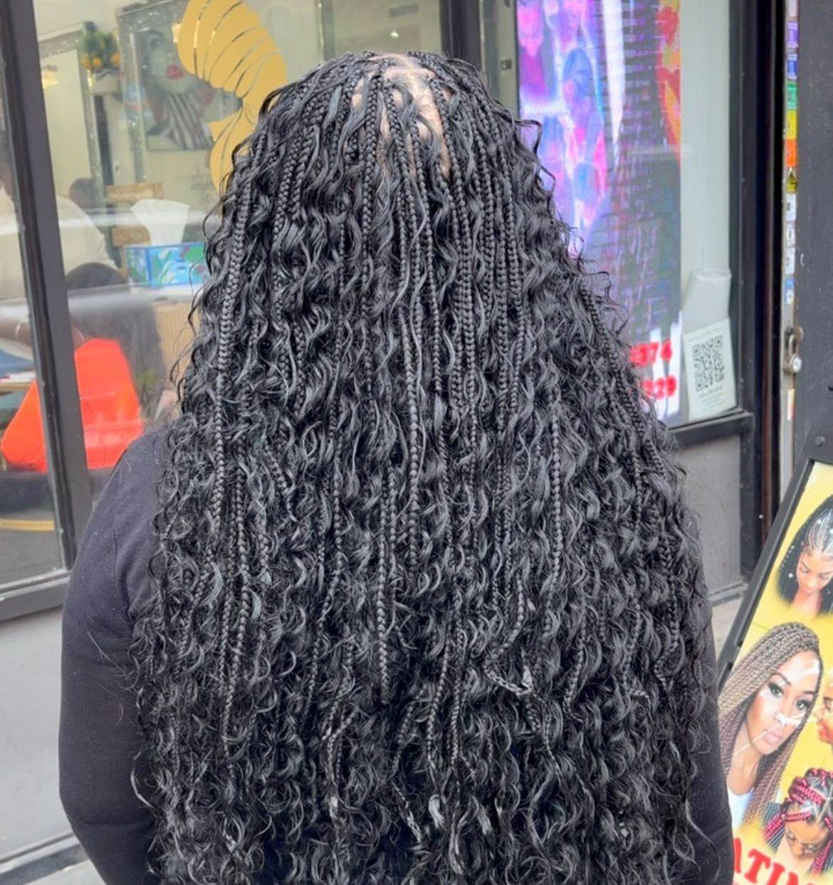 A woman with braids in her hair is standing in front of a store.